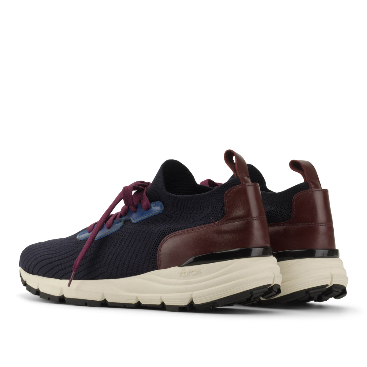 A pair of low-top athletic sneakers shown from a three-quarters side angle. The shoes feature a dark navy blue knit upper, burgundy leather side panels, burgundy laces, a cream-colored midsole, and a black outsole.